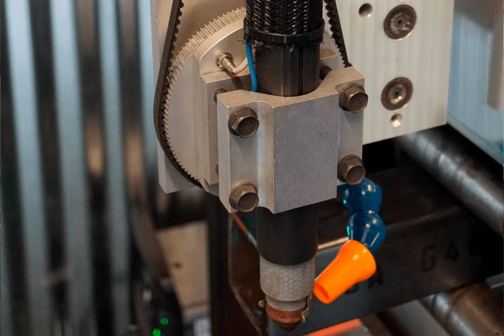 Close-up of CNC plasma torch head on Pipe Dream CNC pipe cutting machine showing precision engineering and cooling system for clean, accurate cuts.